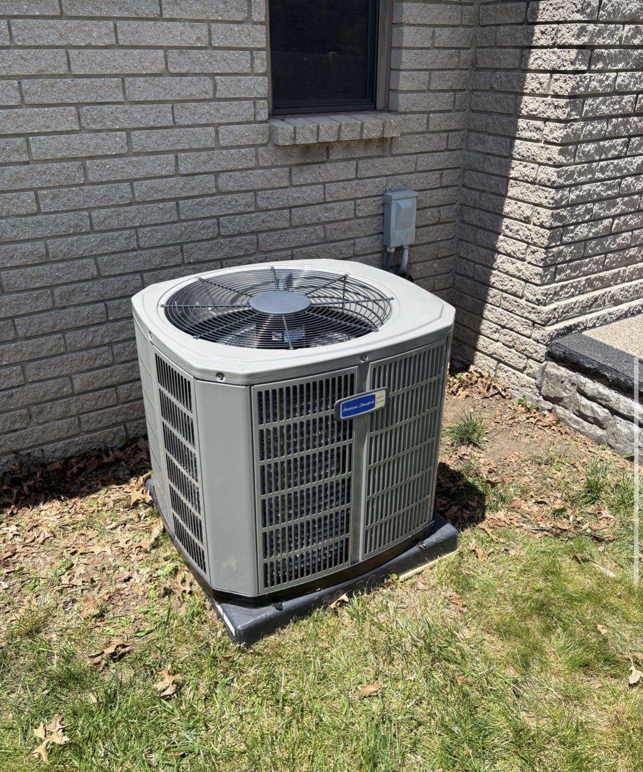 American Standard residential condenser installed beside a brick home